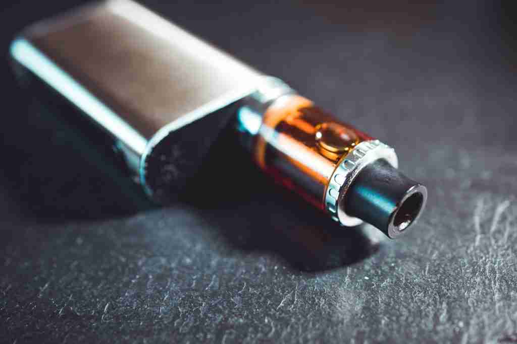 Vape pen metal electronic cigarette with vaping dark background