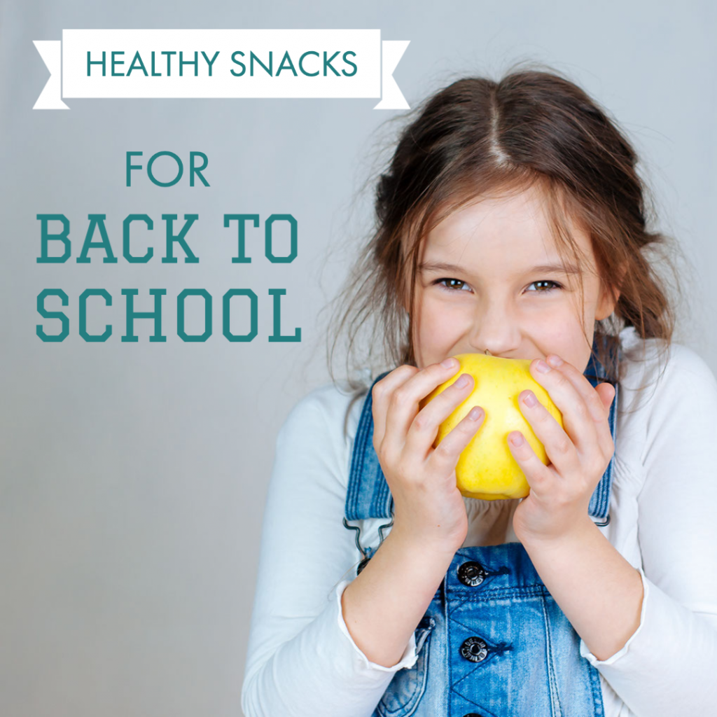 little girl in overalls eating fruit